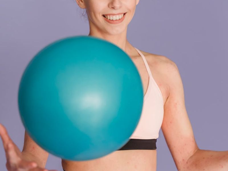 Woman focusing on a balance exercise in grey studio.