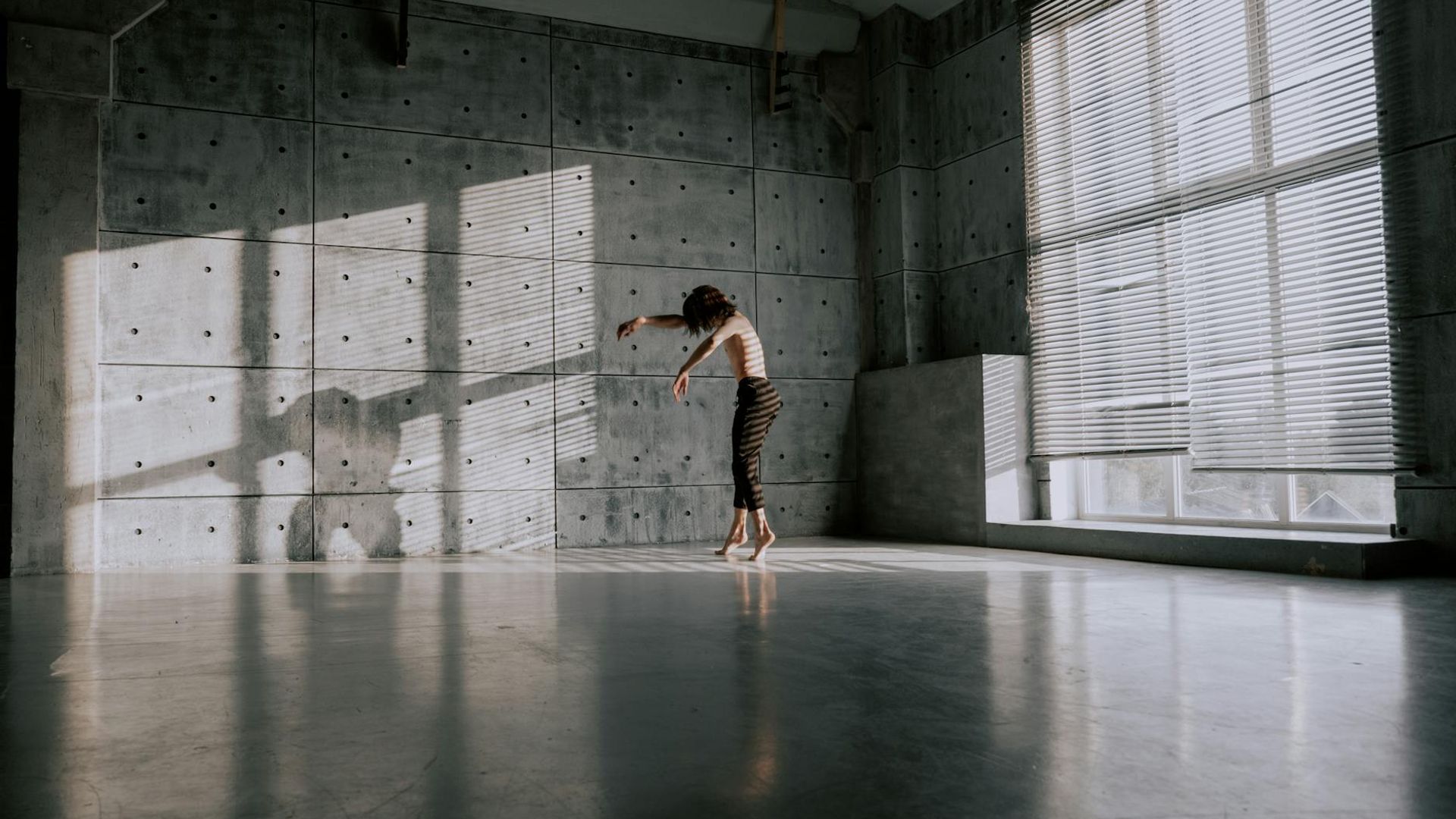 Woman practicing gentle movements in a sunlit room.